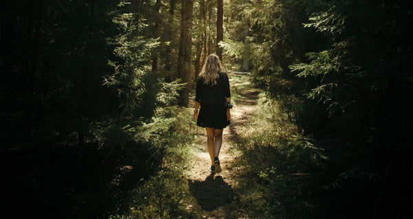 Woman walking in forest with camera